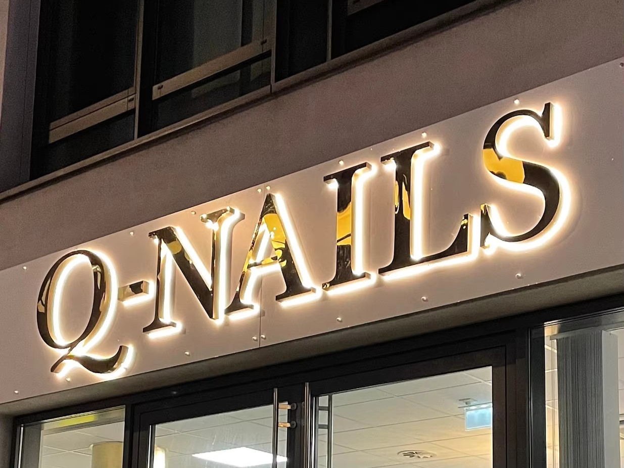 Елітні вивіски з дзеркальним ефектом: проект «Q-NAILS» від «Столиця Неон». Світлова вивіска подібна до «Q-NAILS» із дзеркальними об'ємними літерами та контражурним підсвічуванням, може бути виготовлена компанією «Столиця Неон».